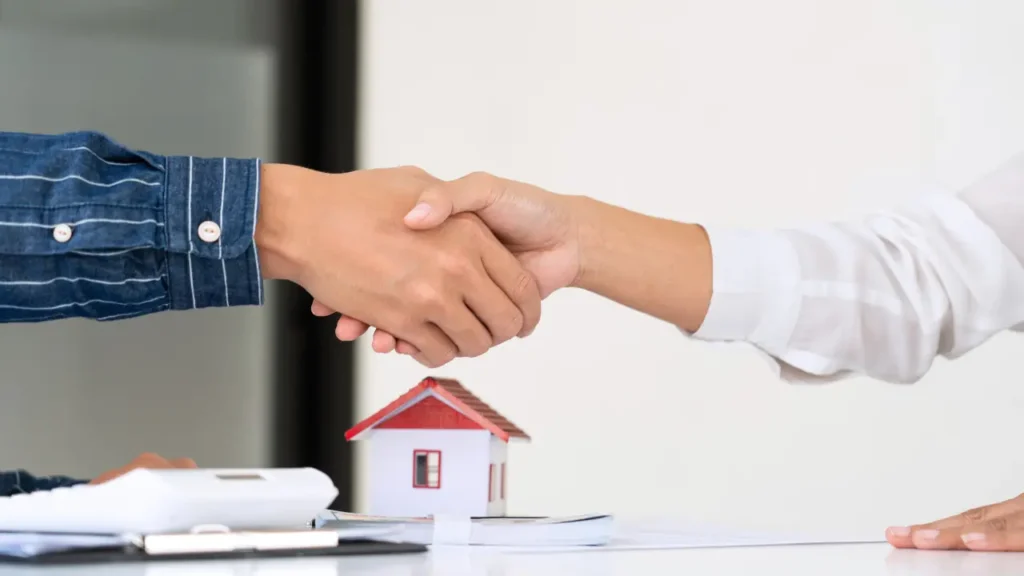 Arms shaking hands over a house